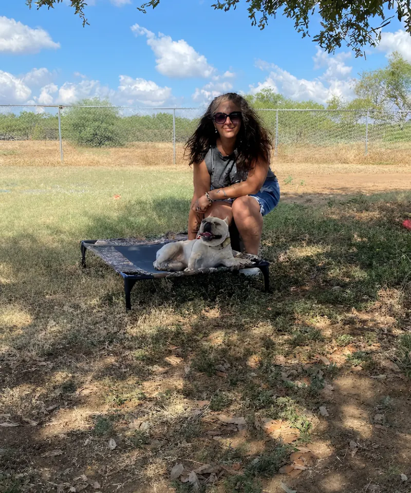 Yasmin with a dog settled on a training cot